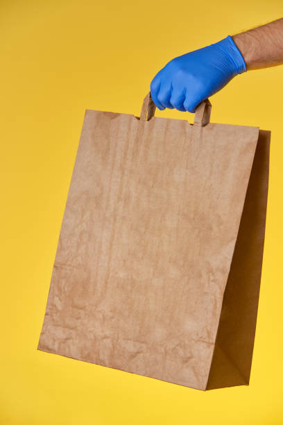 istock Hand in blue glove holds paper bag 1223782761