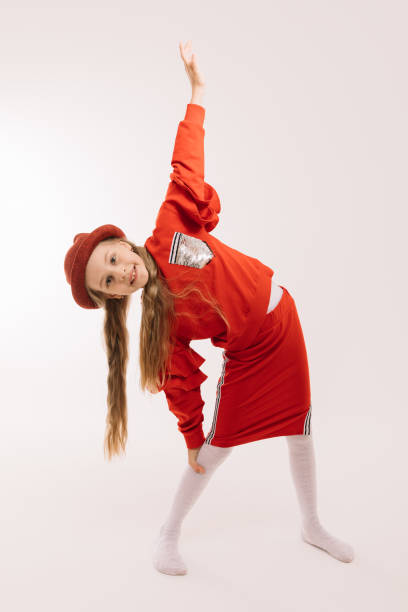 istock Little girl in a red suit and hat posing on a light background 1223783697