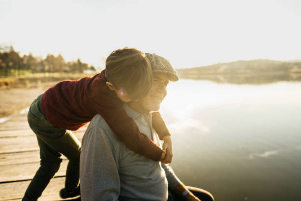Photo of grandfather and grandson on a lake dock
