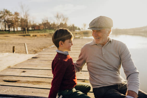 istock Grandfather and grandson sitting on a lake dock 1223788941