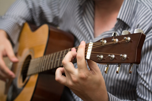 Unknown man playing an acoustic guitar. Selective focus.