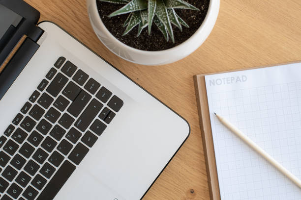 istock Laptop and notepad on wooden desk, workspace top view 1223790429
