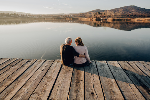 Photo of a mature couple enjoying together on a lake dock
