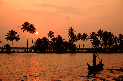Alleppey, India - May 10,2012 : Silhouette of people travel in a wooden boat across the backwaters during sunset in Alleppey, Kerala, India.
