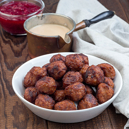 Meatballs in a white bowl, served with cream sauce and cranberry jam, swedish cuisine, square format