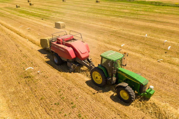 Baler discharging a square Hay Bale, Aerial image Haifa, Israel - May 3, 2020:    Baler discharging a square Hay Bale, Aerial image hay baler stock pictures, royalty-free photos & images