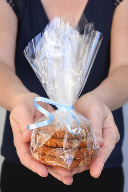 Woman giving ANZAC Biscuits in cellophane wrap