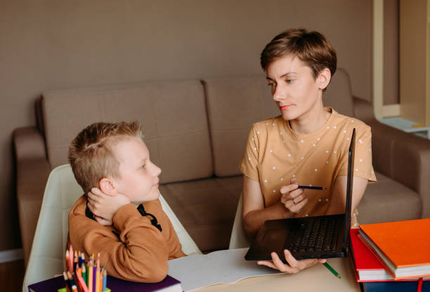 istock Mother teaches child son home online education 1223793149