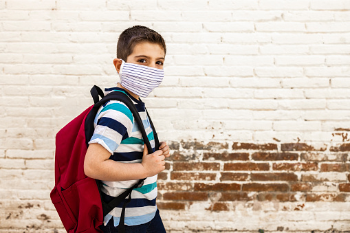 Niño pequeño que va a la escuela con máscara protectora photo