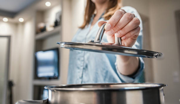 close up woman hand lifting a saucepan lid. - panela com cabo imagens e fotografias de stock