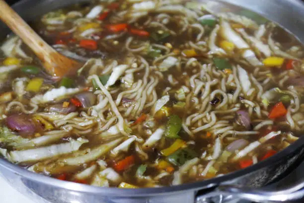 Stock photo showing an elevated view of a meal of homemade spicy thai noodle soup / broth in a green bowl. This is a low calorie meal made with chopped vegetables and rice noodles, which are low in carbohydrate. This dish is part of a healthy eating, low fat diet plan.