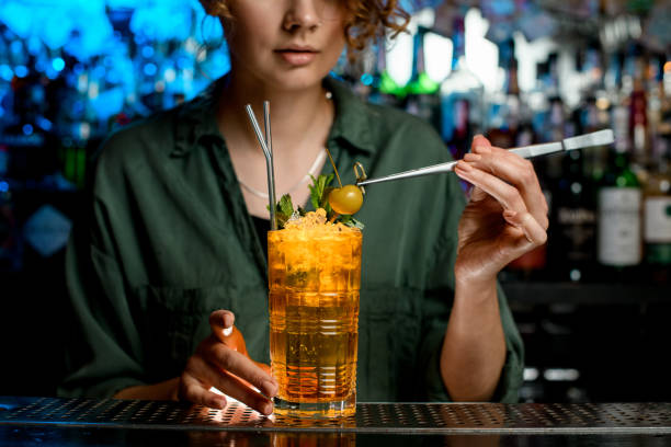 istock Woman using tweezers gently decorates bright cocktail by berry. 1223803747