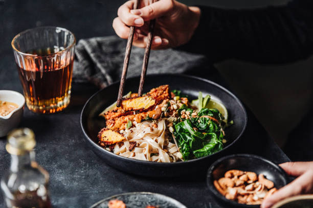 frau isst frisch zubereitete asiatische vegane mahlzeit - fleischersatz stock-fotos und bilder