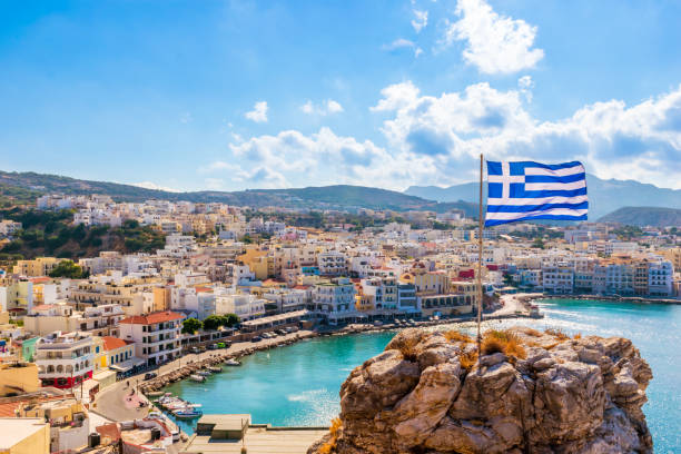 皮加迪亞灣全景,城鎮和港口與希臘國旗,卡爾帕索斯島,希臘 - 希臘國旗 個照片及圖片檔