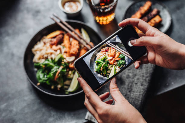 Hands of cook photographing Asian vegan dish Hand of a chef taking photograph of vegan dish on table with a mobile phone. Hands of cook photographing meal. salad dressing photos stock pictures, royalty-free photos & images
