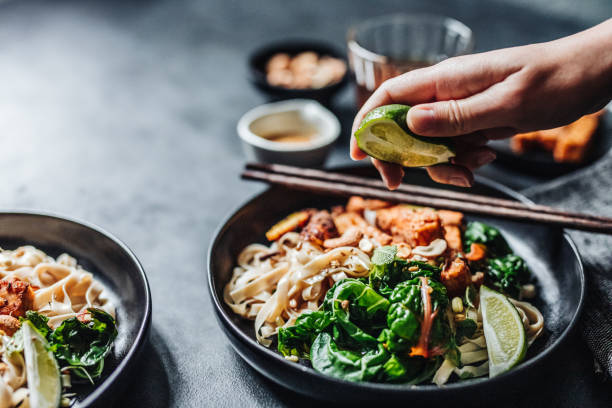 chef añadiendo lima a un plato vegano - comida asiática fotografías e imágenes de stock
