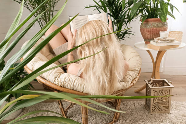 istock Woman reading a book, relaxing in boho room. 1223804056