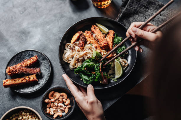 istock Woman eating Asian dish with chopsticks 1223804100