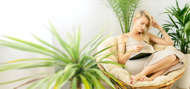 istock Woman reading a book, relaxing in boho room. 1223804160