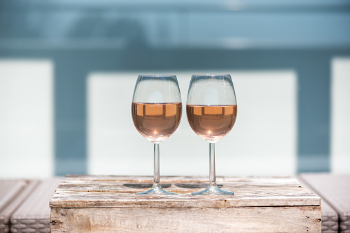 Two rose wine glasses on a small wooden table in springtime