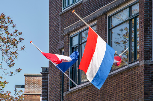 Rotterdam, The Netherlands, May 4, 2020: two flags half-mast in a residential street on Remembrance Day, 75 years after the end of World War Two