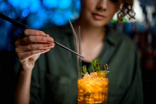 istock Woman using tweezers decorates cocktail by glass sticks 1223808006