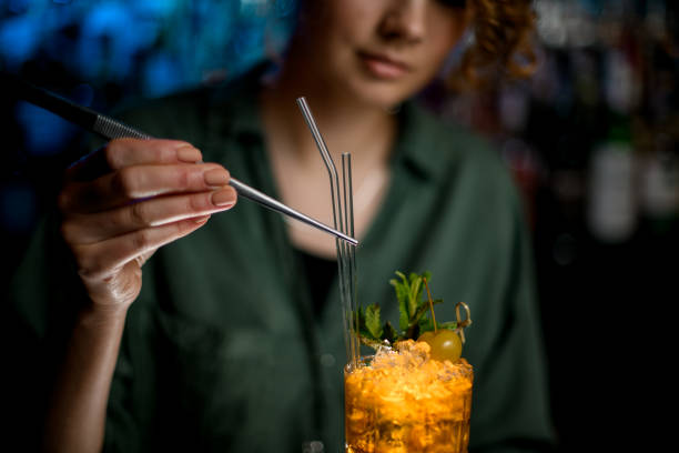 istock Woman bartender decorates finished cocktail by glass sticks. 1223808030