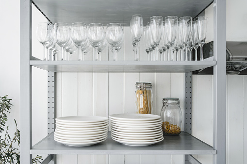 Kitchen housewares, wine glasses and plates displaying in a domestic kitchen cabinet