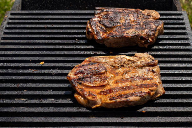 carne a la parrilla. deliciosos filetes en una parrilla caliente. - strip steak steak barbecue grill cooked fotografías e imágenes de stock