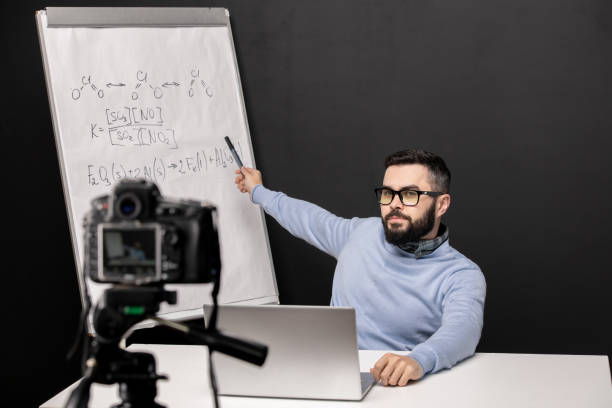 istock Young confident teacher pointing at whiteboard with chemical formulas 1223814413