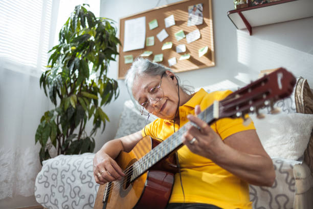 istock Senior woman playing guitar ay home 1223816228