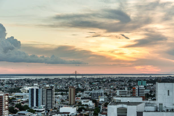 vista sulla città di manaus al tramonto con ponte rio sullo sfondo nella regione amazzonica del brasile, sud america - industry water sky architecture foto e immagini stock