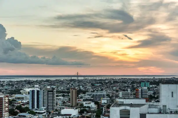 Aerial view at sunset with a beautiful cloudy sky over the urban city of Manaus in the Amazon region of north Brazil in South America, with high rise buildings & the Rio Negra bridge over the Rio Negra river in the background