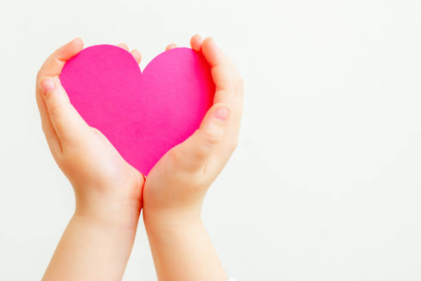 istock Paper pink heart in child's hands. 1223822830