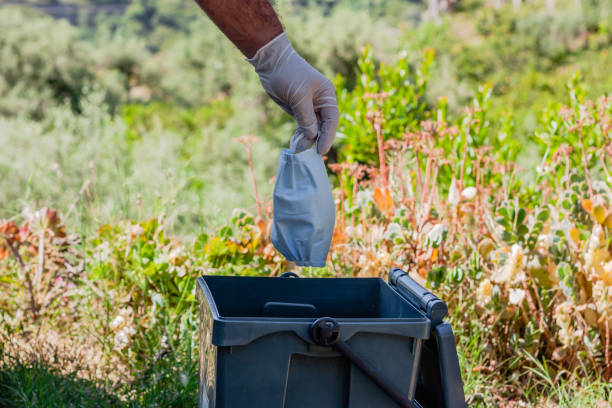 istock Man throwing used surgical mask into recycling bin. Waste disposal problem in coronavirus times, covid-19. 1223822975