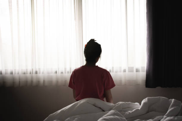 우울한 아시아 여성은 슬프고 외로운 아침에 침대에 앉아 있는 느낌이 있습니다. - women depression window sadness 뉴스 사진 이미지