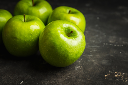 Close-up green apples on the rustic wooden background. Selective focus. Shallow depth of field.