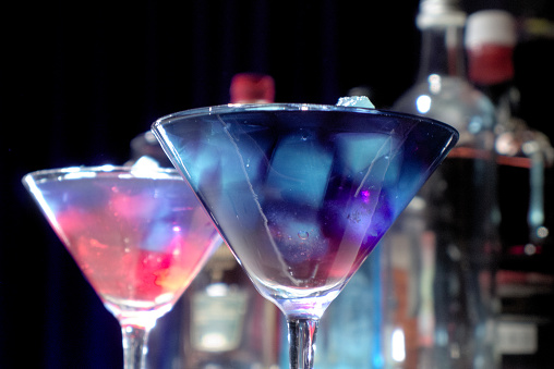 Purple cocktails with colourful ice cubes served in martini glasses