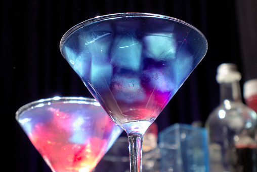 Purple cocktails with colourful ice cubes served in martini glasses