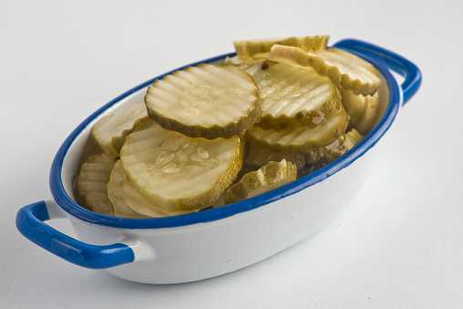 Dill pickles marinated in extra virgin olive oil, vinegar, red pepper flakes and herbs and spices. Photographed on white background. Classic Mediterranean, Greek or Italian garnish or ingredient.