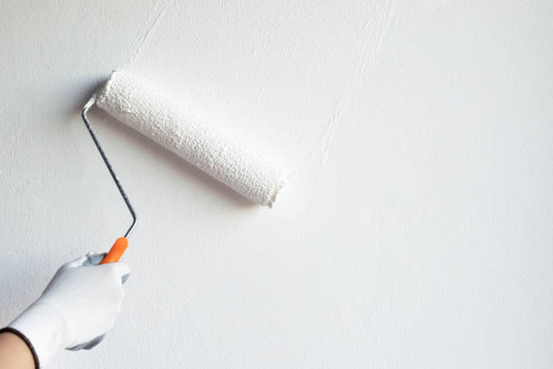 istock The carpenter is painting white on the wall. 1223830544