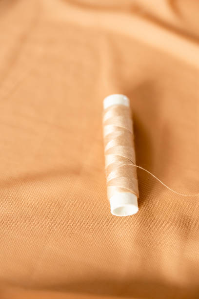 Sewing background with tailor equipment on the peach colored cloth. Selective focus.