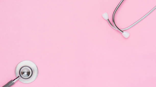 istock Top table view or flat lay of stethoscope on pink paper background by eartips and bell diaphragm located in each corner of frame middle is space for text, banners or contents. 1223831915