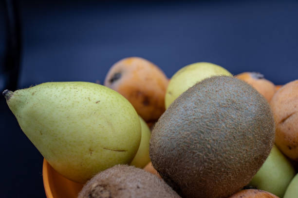 ein korb mit frischem obst, kiwi und medlars. vitamin c wichtig für das immunsystem. - lucy pearson stock-fotos und bilder