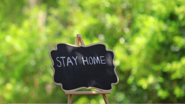 STAY HOME lettering on black chalkboard. Covid-19 coronavirus concept background.