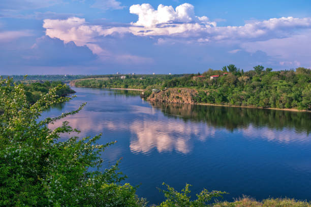 istock Beautiful spring landscape with river, lush forest, cliffs and white clouds 1223836040