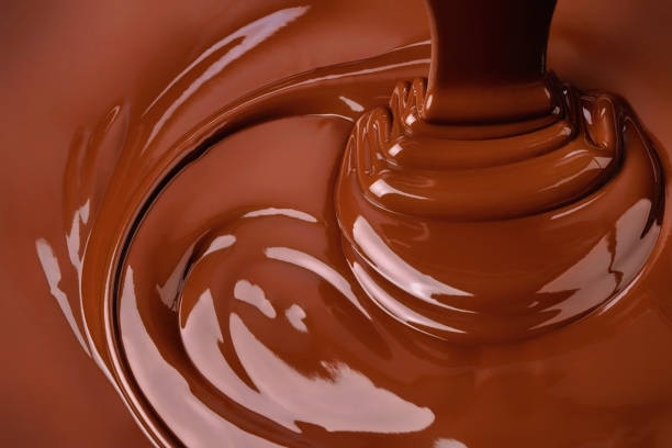 поток расплава шоколада распространяется волнами. горячий фон какао - расплавленный стоковые фото и изображения