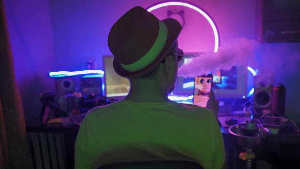 istock Smokers Hookah looks mobile phone Working with computer In a dark room lit by neon lights. Work from home concept, quarantine and self-isolation concept 1223839423