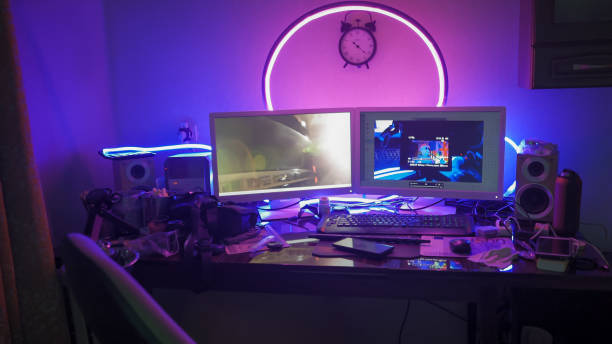 istock Modern work place of creative man or freelancer. Table with computer and digital gadgets on it in home interior with neon glows 1223840274