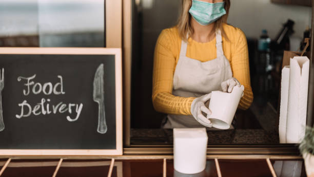 istock Young woman preparing delivery food inside takeaway restaurant during Coronavirus outbreak period - Worker inside kitchen cooking healthy food for home order service - Focus on hands 1223840286